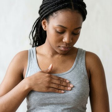 Young Woman Touching Her Chest In Thoughtful Pose Against Neutral Background