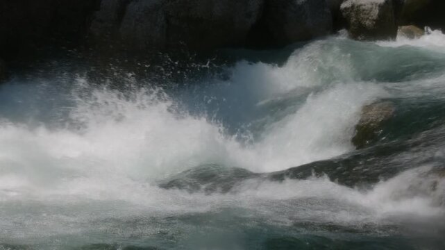 Whitewater chute rushing over river rocks with intense splashing foam
