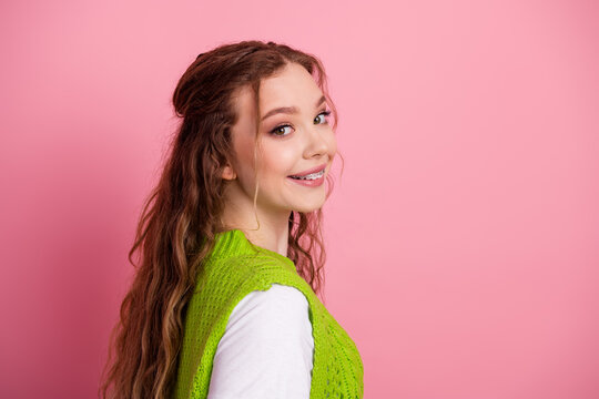 Young female student smiles in a bright pink background wearing a lime green knit vest for fashion lifestyle shoot