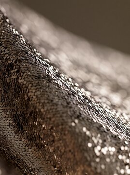 Close-up of a fabric with a textured surface. the fabric appears to be made up of small, shiny sequins that are arranged in a repeating pattern.