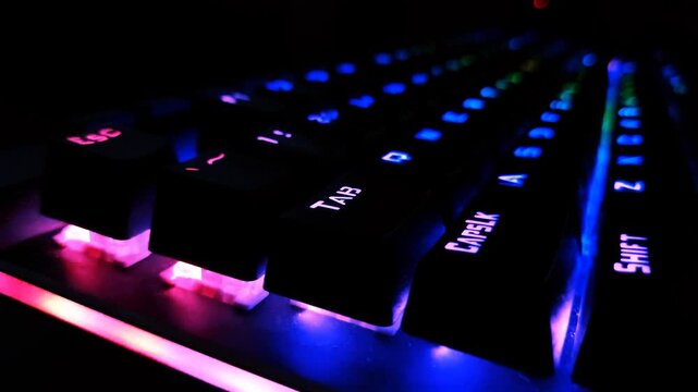 Person's hands typing continuously on a blue backlit mechanical laptop keyboard. Suitable for software development, IT support, online gaming, data science, and dark mode computer work concepts.
