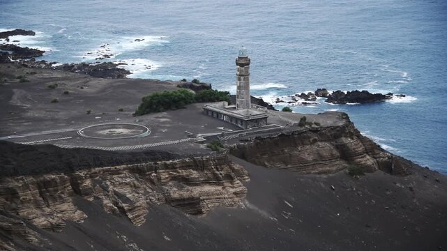Farol dos Capelinhos lighthouse half-buried in volcanic ash on the Capelinhos headland, Faial, Azores, Portugal