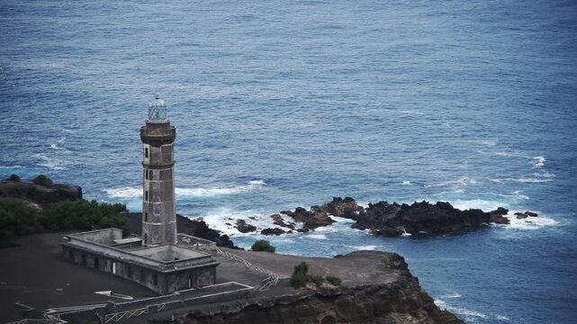 Capelinhos lighthouse above the lava reef and Atlantic surf on the Capelinhos volcano headland, Faial, Azores
