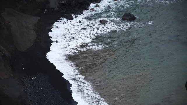 Aerial view Surf breaking on black volcanic sand below pale ash cliffs at Capelinhos, Faial, Azores, Portugal