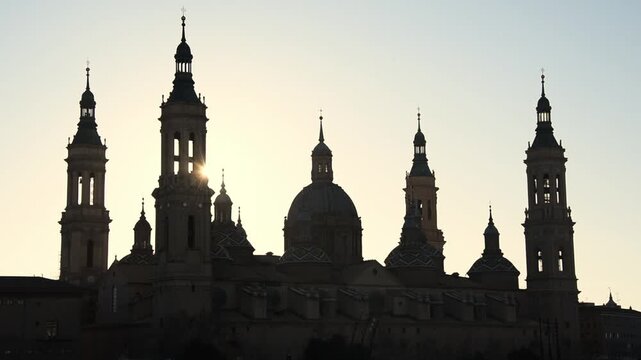 Towers, dome and tiled cupolas of the Basilica del Pilar in silhouette, Zaragoza, Aragon, Spain, at golden sunrise