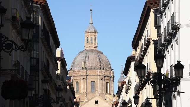 The lantern and dome of the Basilica del Pilar seen down a narrow old-town street, Zaragoza, Aragon, Spain, in winter sun
