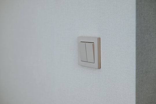 A light switch is mounted on a plain wall, showcasing a simple design.