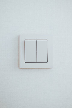 A light switch is mounted on a smooth white wall, featuring a simple design with two switches.