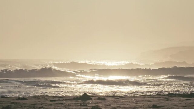 Backlit waves glitter as they roll ashore at Oyambre, Cantabria, Spain