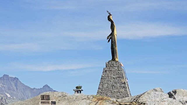 Madonna delle Nevi in profile on her cairn plinth, Monte Moro Pass, Valais, Switzerland, gilded against pale blue sky