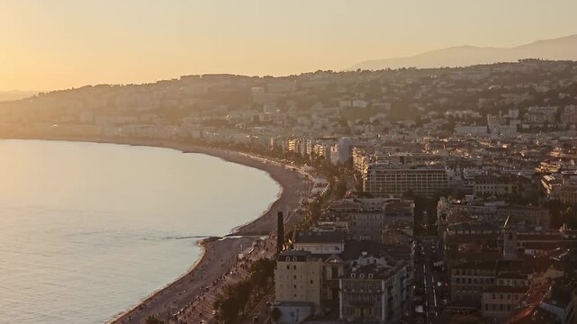 Aerial view Baie des Anges curving past the old town, Nice, Alpes-Maritimes, France, the city stretching to hazy hills at golden sunset