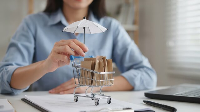 Person placing a small toy umbrella over a miniature shopping cart