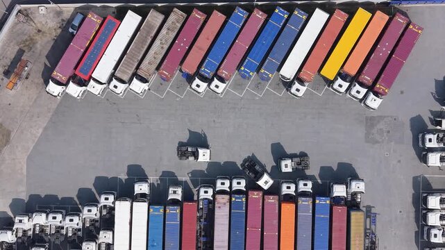 Aerial view of a logistics facility with rows of colorful freight trailers and trucks parked in a transport hub in Cusago, Lombardy, Italy.