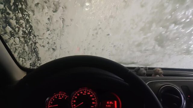 Car wash interior pov showing soap patterns on the windshield from inside a moving vehicle