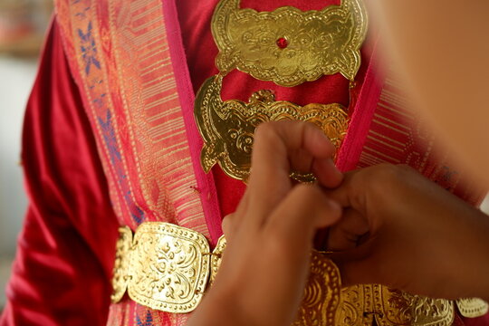 Close-up shot of hands adjusting gold traditional ornaments for cultural event