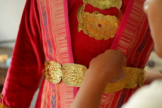 Cultural heritage detail of hands decorating traditional red and gold costume