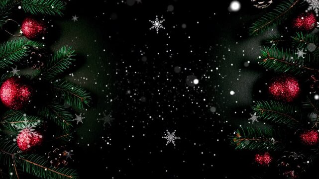 Dark elegant Christmas background with pine tree branches red baubles and falling winter snow