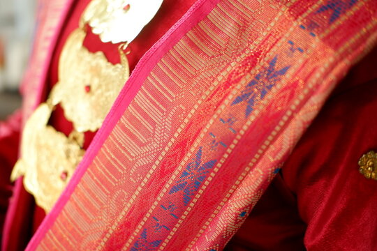 Detail of hands putting on gold necklace and traditional ethnic costume