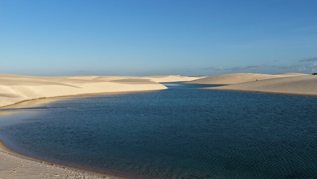 Aerial view of Parque Nacional dos Lencois Maranhenses featuring vast white sand dunes and crystal clear blue lagoons in Atins, Maranhao, Brazil.