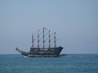 Pirate-themed tourist sailing ship with Turkish flags on calm blue sea © Вікторія Мельник