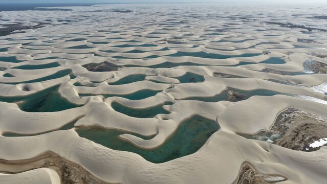 Aerial view of Parque Nacional dos Lencois Maranhenses featuring vast white sand dunes and turquoise lagoons in Atins, Maranhao, Brazil.