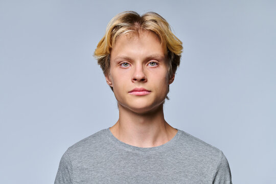 Portrait of handsome teenage boy looking at camera on grey background
