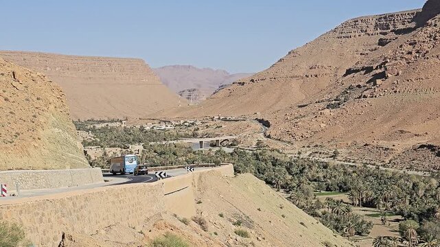 Road bridge and palm groves on the valley floor of the Ziz Canyon below rugged cliffs, Draa-Tafilalet, Morocco