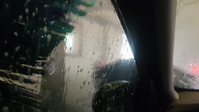 An automatic car wash. View from the inside. Large rollers wash the sides and windows of the vehicle.