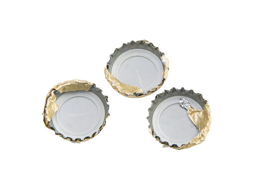 Three bottle caps, each with torn golden foil
