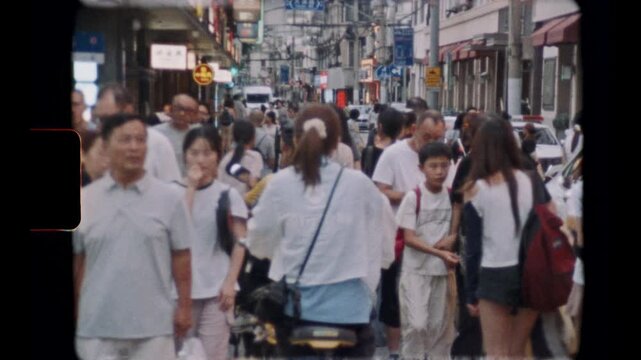 SHANGHAI, CHINA - AUGUST 1, 2026: Pedestrian crowd walks along a Shanghai shopping street as a cyclist passes, filmed on Super 8 film