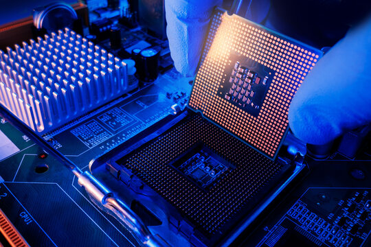 Gloved hand of master placing cpu processor into motherboard socket with neon blue and orange lighting for modern AI data center background, Probe view