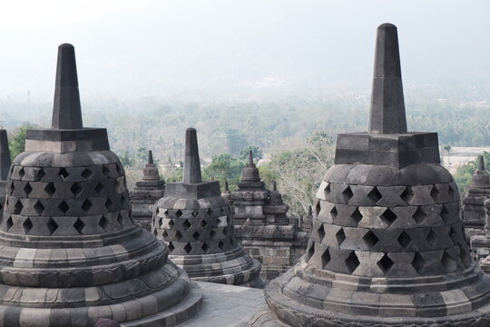 Row of Bell Shaped Perforated Stupas Overlooking Hazy Valley Landscape at Borobudur Temple