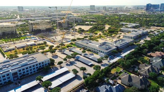 Yellow tower cranes rise above active Hall Park commercial parcels near Warren Parkway. Sprawling suburban subdivisions border dense business district construction, Frisco, Texas