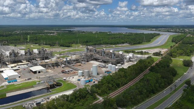 Aerial view of FPL Sanford Power Plant featuring industrial infrastructure, storage tanks, and cooling systems surrounded by lush greenery and a lake in DeBary, Florida, United States.