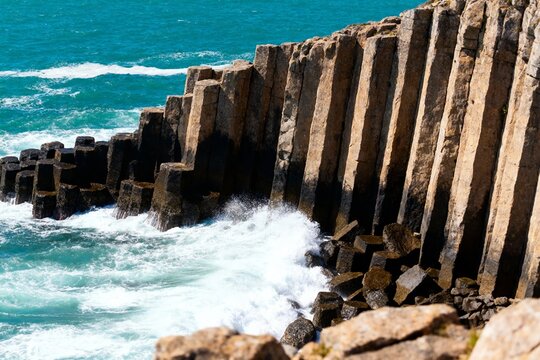 Basalt columns at coastal cliff with waves crashing against rock formations