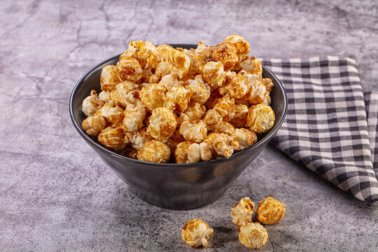 Caramel popcorn in dark bowl with checkered cloth