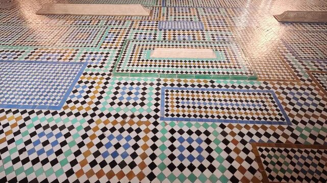 Carved marble grave slabs set in checkerboard zellij, Saadian Tombs, Marrakech, Morocco, warm light raking the tiled floor