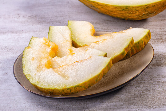 Sliced piel de sapo melon on ceramic plate with textured background