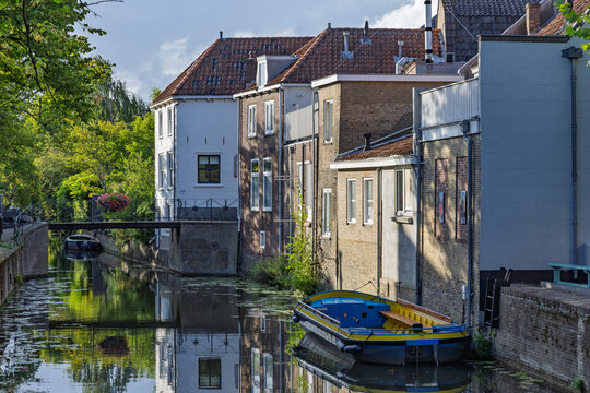 Oudewater, Netherlands: Picturesque canal view featuring traditional historic Dutch houses and a small boat moored along the quiet waterway in Oudewater.