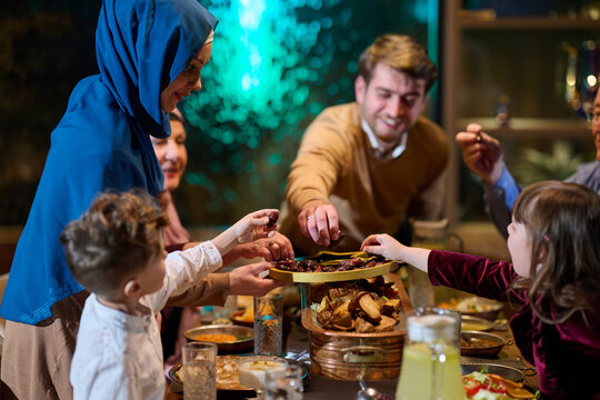 Family Sharing Iftar Dinner at Home: Muslim Parents and Children Reaching for Dates and Food