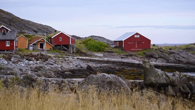 Cluster of red and ochre rorbuer on rock at Ostre Nesland, Flakstadoy, Lofoten, Norway