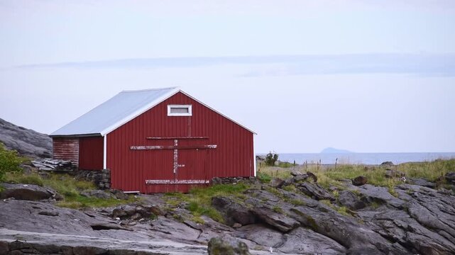 Weathered red boathouse on the shoreline at Ostre Nesland, Flakstadoy, Lofoten, Norway