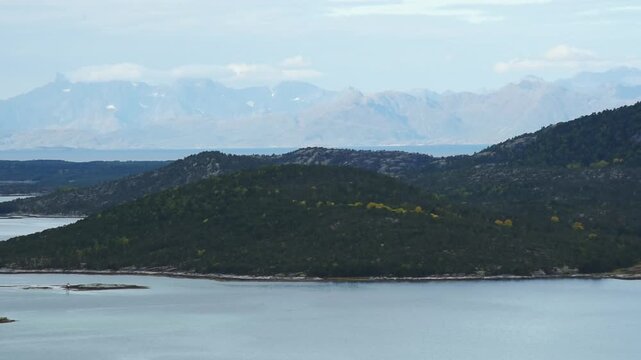 Wooded island in the sound with a hazy mountain wall behind, near Bodo, Nordland, Norway