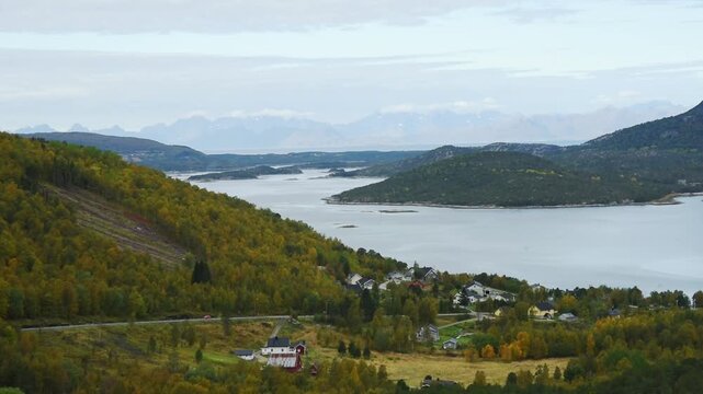 Coastal village and farm above the fjord with distant peaks, near Bodo, Nordland, Norway