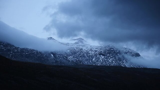 Snow dusted peaks half hidden by drifting cloud at the Arctic Circle, Nordland, Norway