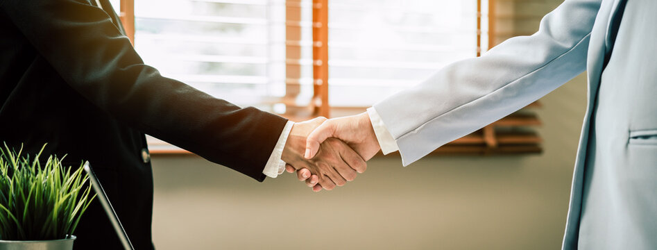 Close up of business people shaking hands in the office.