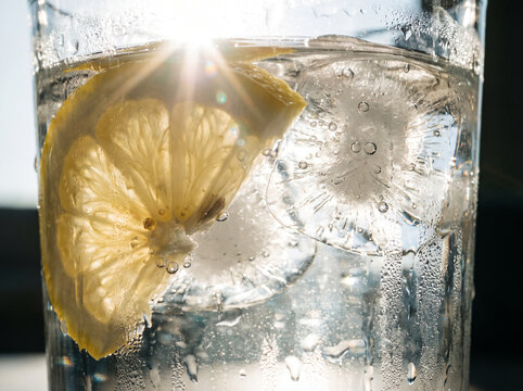Dynamic splash of fresh lemon slice falling into cold ice water.