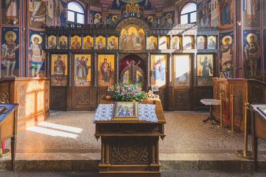 Interior of a traditional Orthodox church with ornate iconostasis and frescoes.