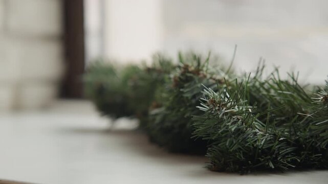 Close up of green pine garland with small brown cones softly lit and stationary on white surface. detailed texture shows person needles and natural arrangement set against out of focus