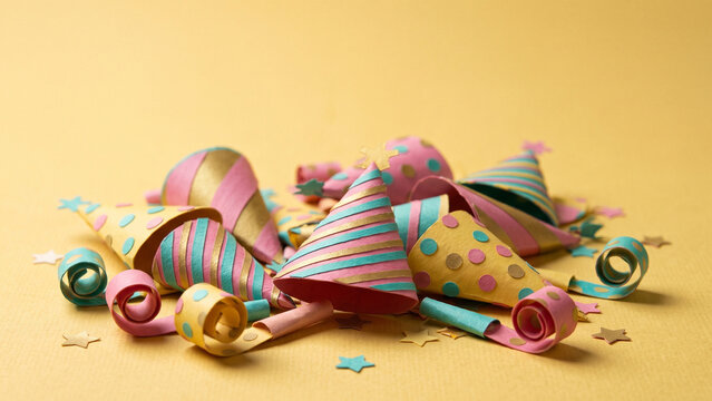 Colorful party hats and blowers for a festive new year celebration with stars on a yellow background.